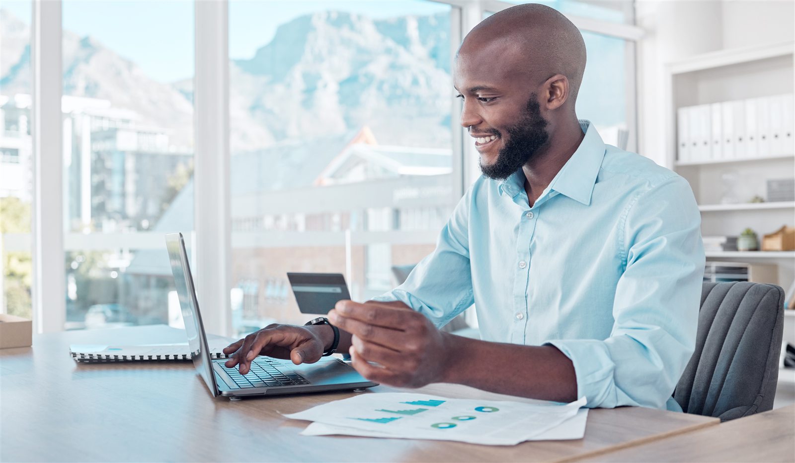 A South African practice owner updating their banking details online with a bank card and laptop